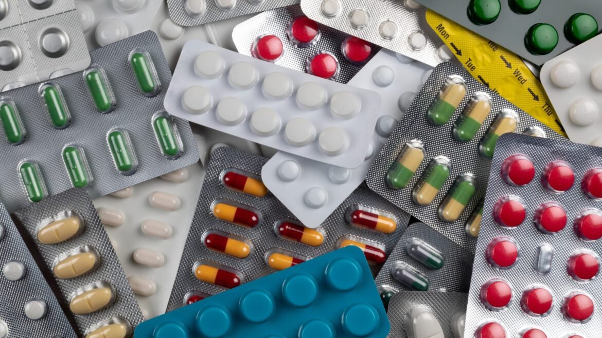 Assorted blister packs with colorful pills and capsules scattered across a surface.
