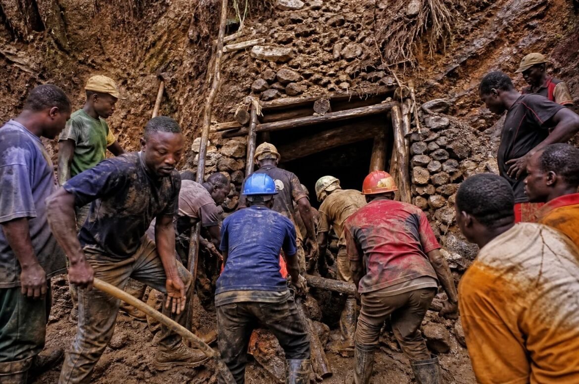 Group of miners digging at the entrance of a muddy mine, wearing helmets and dirty clothes.
