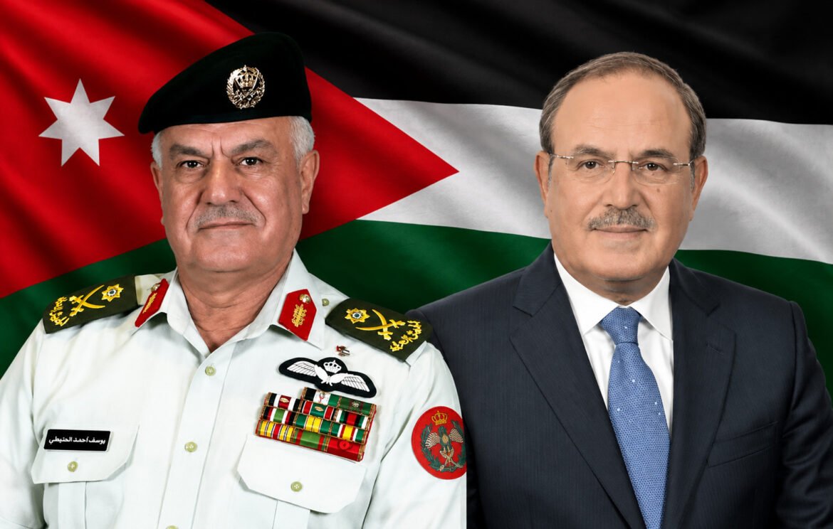 Two men posing side by side in front of a Jordan flag: a senior military officer in a white dress uniform with medals next to a man in a dark suit and blue tie.