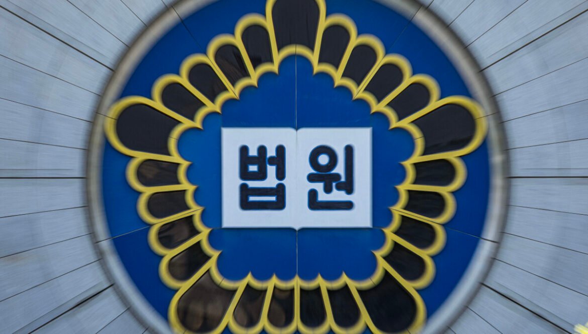 Circular emblem with blue background and yellow petal border; open book with the Korean word 법원 (court) on white pages.
