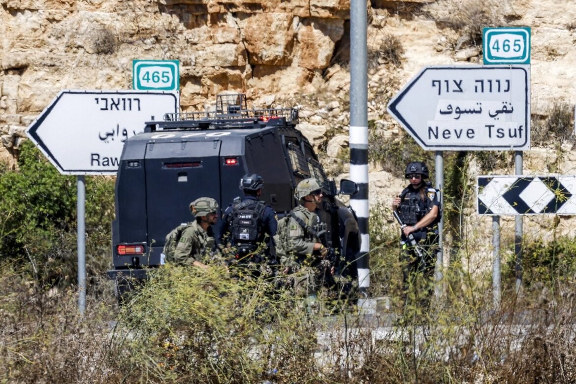 Israeli armored vehicle with soldiers beside it on a rural road; road signs in Hebrew and Arabic visible (Route 465, Neve Tsuf).2) Armed security team beside a black armored vehicle at a highway junction, signs show Route 465 and Neve Tsuf.3) Military squad in tactical gear near an armored vehicle by a road sign pointing to Neve Tsuf (Route 465).4) Group of soldiers with a armored vehicle at a roadside, road signs in Hebrew and Arabic indicating directions.5) Security forces in a desert setting with an armored vehicle and oncoming road signs for Route 465 and Neve Tsuf.
