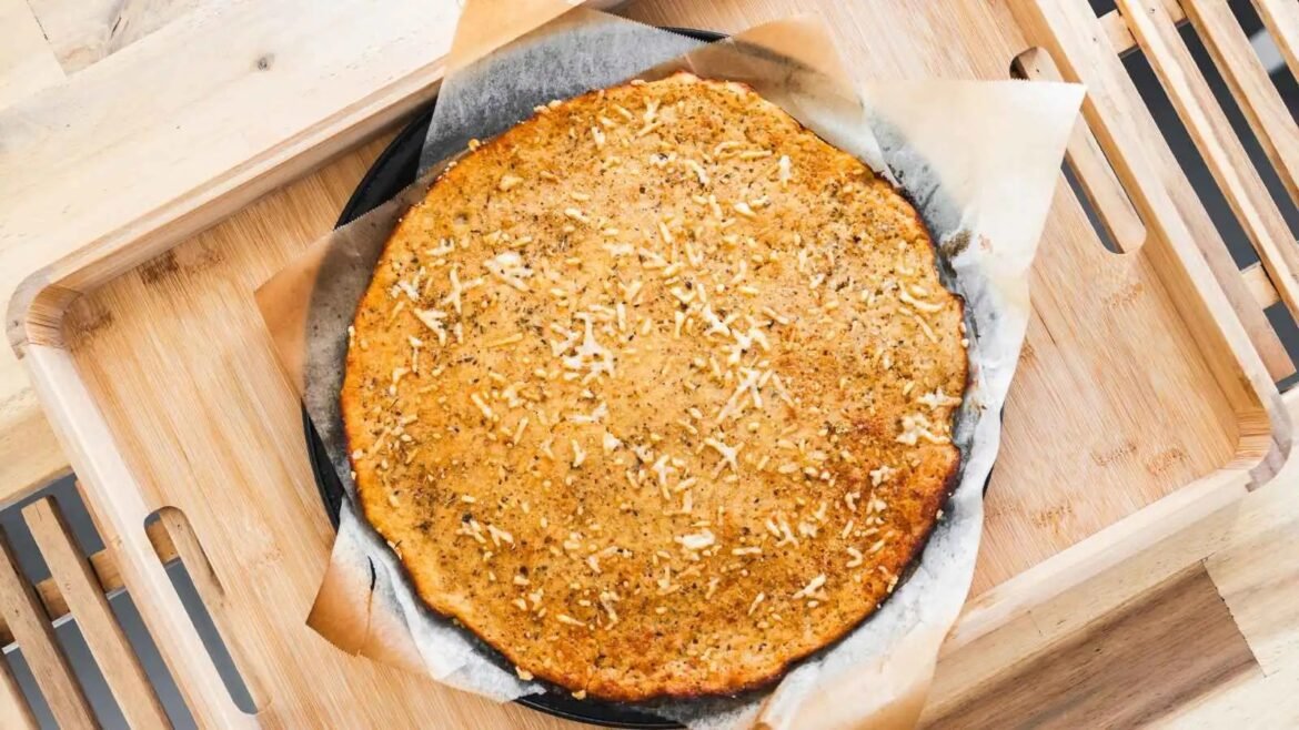 Round baked cake or tart with shredded coconut on parchment-lined pan resting on a wooden serving board.