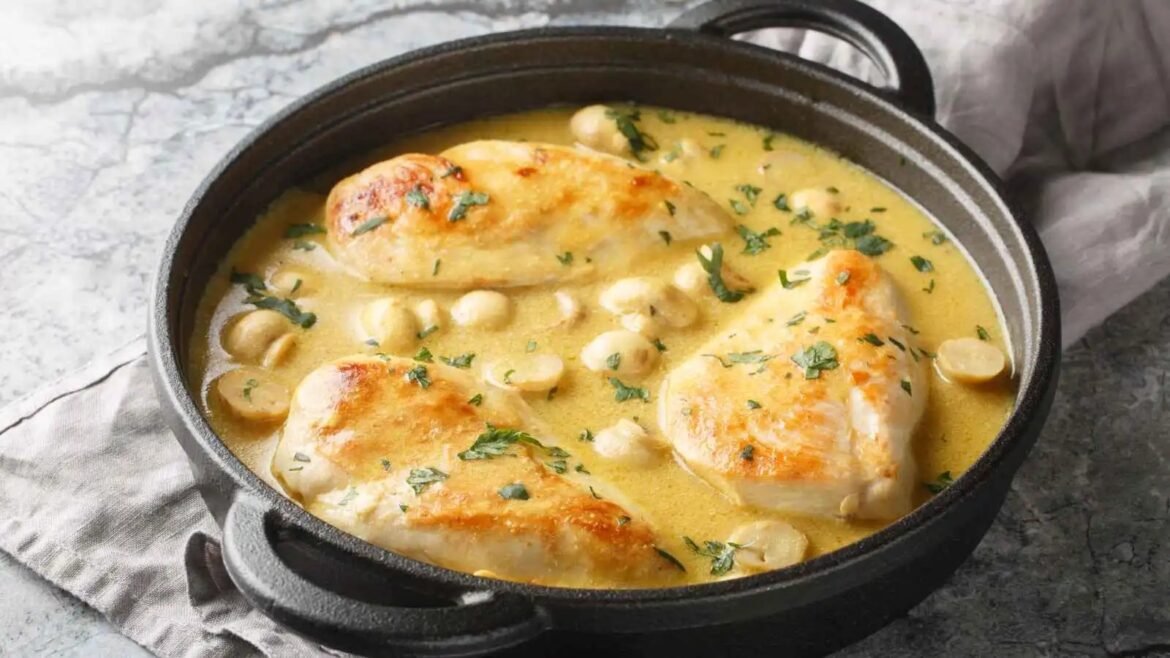Chicken thighs in a creamy garlic sauce with gnocchi and chopped parsley in a dark skillet.