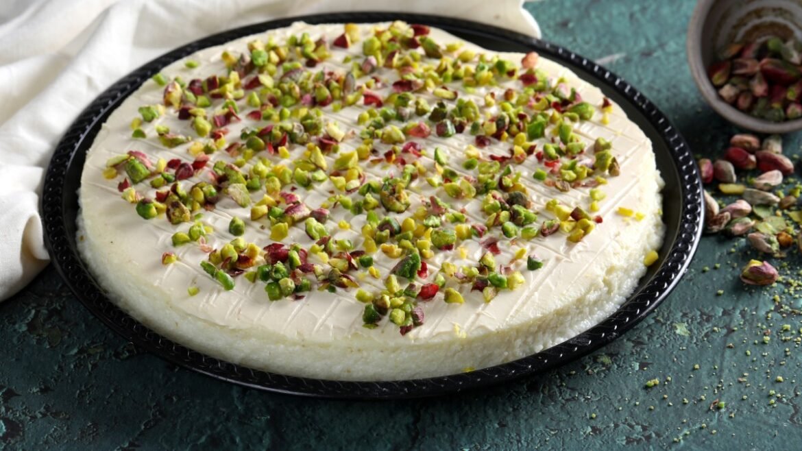 Creamy cheesecake on a black platter topped with chopped pistachios