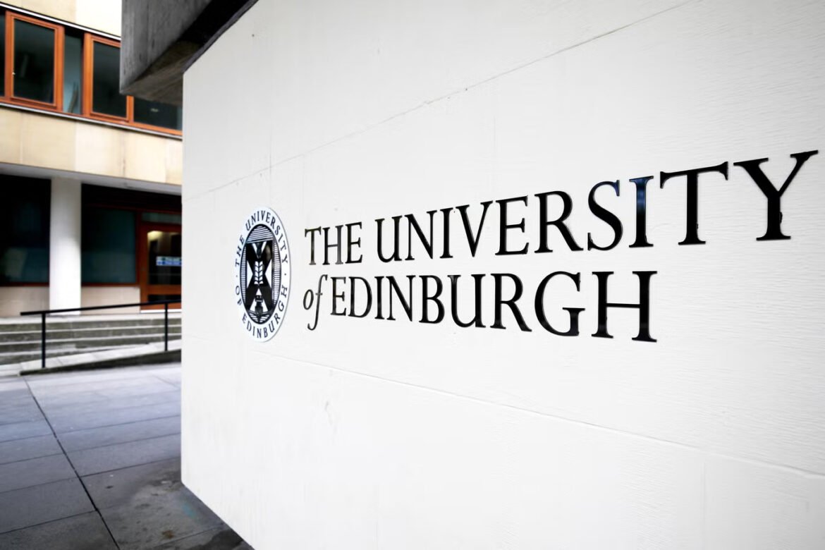 The University of Edinburgh sign and circular seal on a white wall at a campus courtyard exterior.