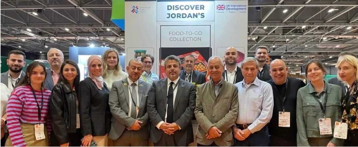 Group of professionals at a trade show posing in front of a Jordan tourism booth that reads 'Discover Jordan's' and 'Food-to-Go Collection'.