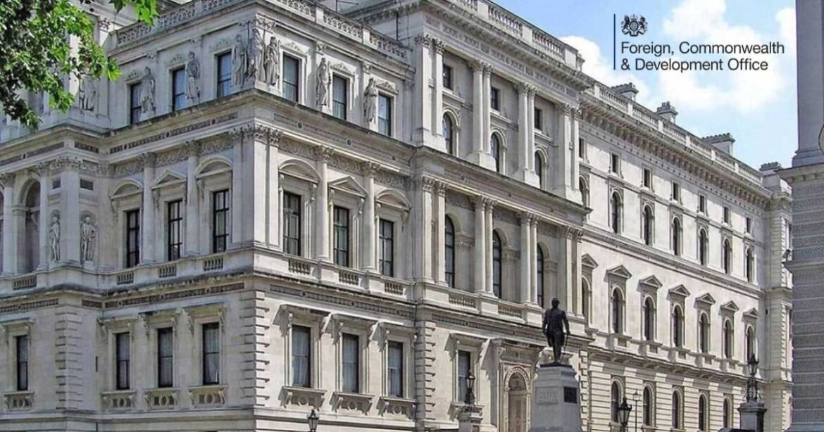 Historic neoclassical building with ornate stone facade and a statue in front of the entrance.