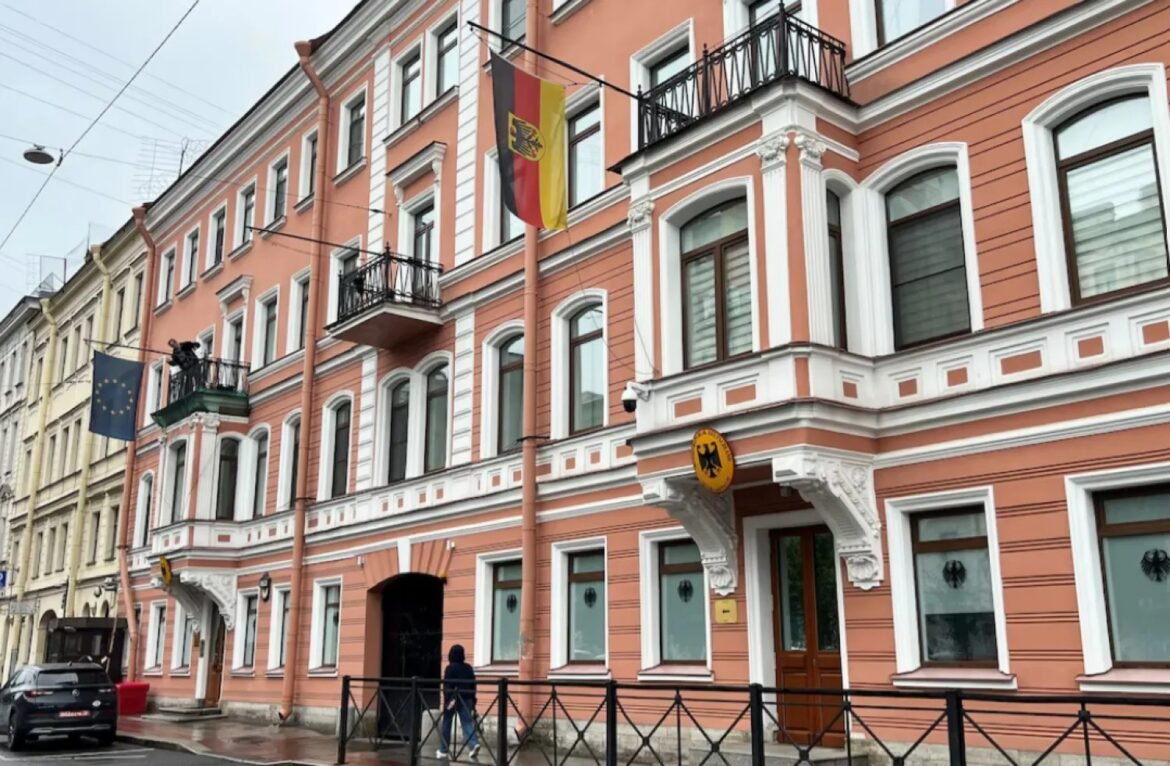 Orange three-story historic building with white decorative trim and wrought-iron balconies, flags hanging from the facade along a street.