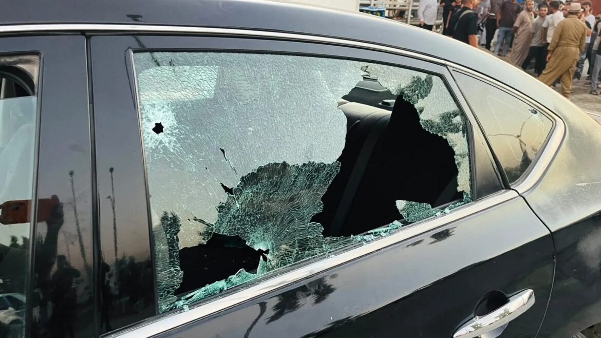 Black car with a large shattered rear side window and broken glass on the door frame.