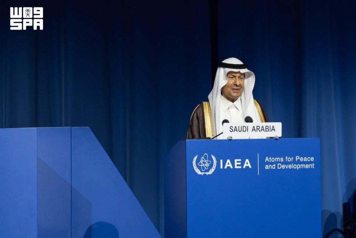 Saudi Arabia delegate in a white thobe and ghutra speaks at an IAEA conference podium with a blue backdrop.