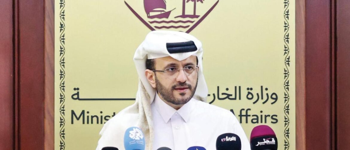 Male speaker in white thobe and headscarf at a press conference with multiple microphones in front; backdrop reads Ministry of Foreign Affairs in English and Arabic.