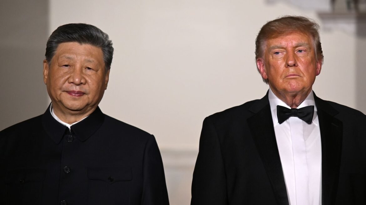 Two men in formal attire stand side by side against a neutral background, looking ahead with neutral expressions.