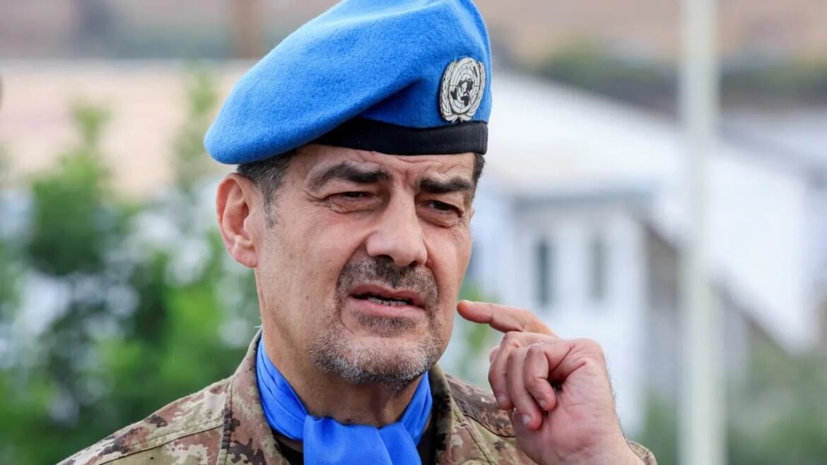 Close-up of a man in a blue UN beret and camouflage uniform, touching his lips thoughtfully.