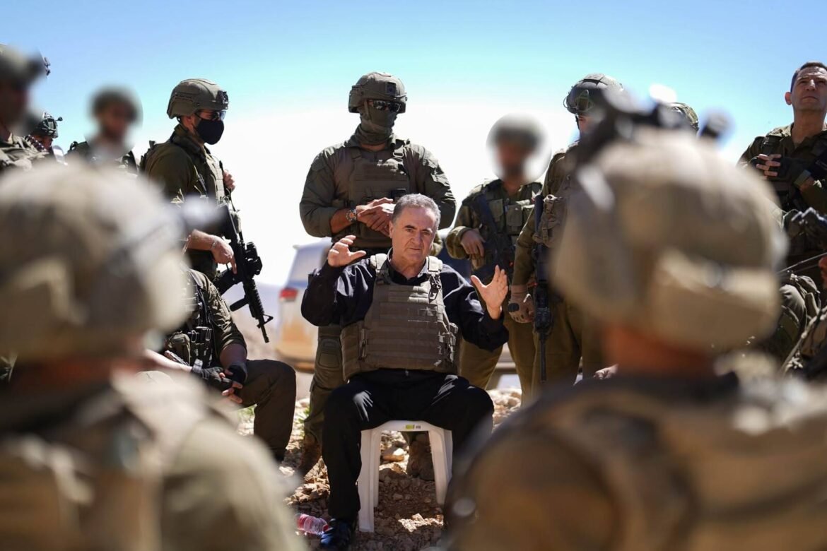 Middle-aged man in a tactical vest sits on a white chair, surrounded by armed soldiers in desert camouflage outdoor setting.