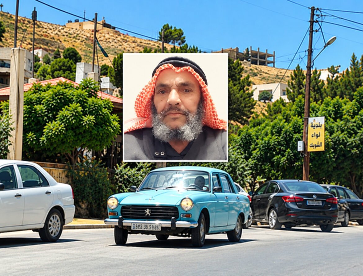 A vintage blue car driving on a sunny street with greenery and buildings; an inset photo of a bearded man wearing a red-and-white headscarf appears in the center.