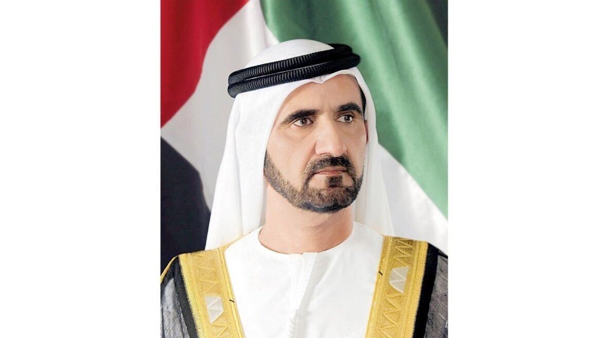 Portrait of a man in traditional Emirati attire (white kandura with gold-trimmed bisht and black agal) against a flag backdrop, looking to the side.