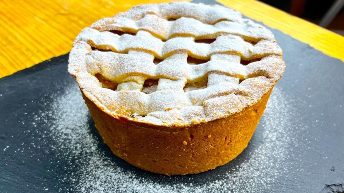 Lattice-topped fruit tart dusted with powdered sugar on a slate serving board