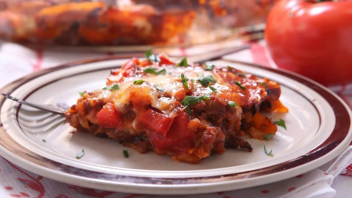 Slice of cheesy meat lasagna with tomato sauce and parsley on a plate.