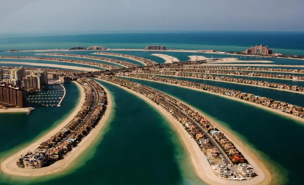 Aerial view of Palm Jumeirah, Dubai: a palm-shaped archipelago with villa-lined fronds and surrounding blue water.