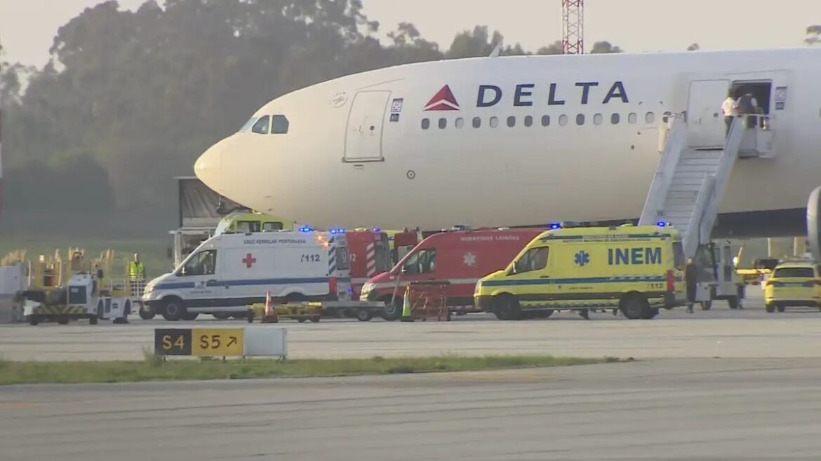 Delta airplane on the tarmac with emergency vehicles beside it, including a blue‑and‑white ambulance and a yellow INEM ambulance, indicating an incident or medical standby.
