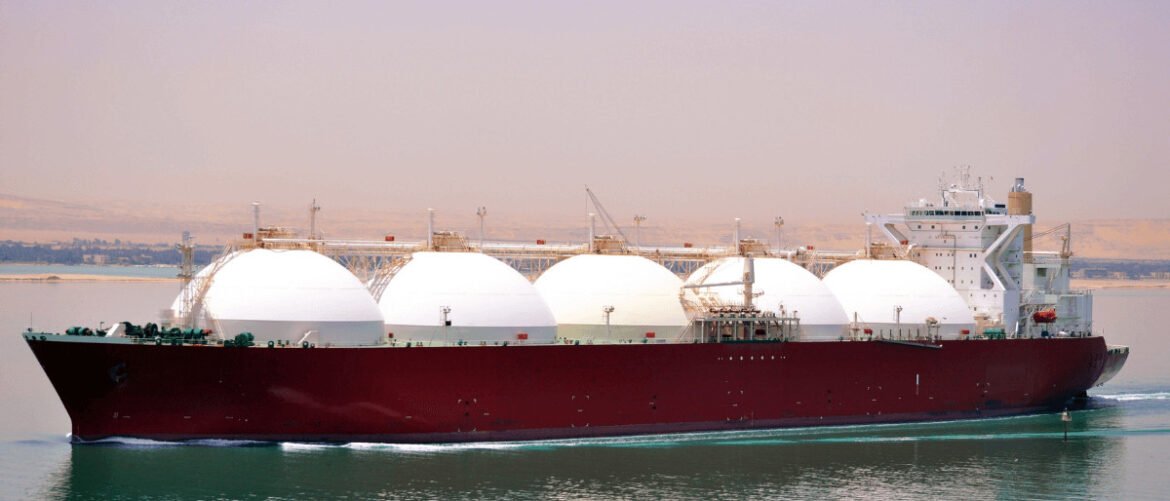 Large LNG carrier sailing on calm water with white spherical gas tanks and a white bridge.
