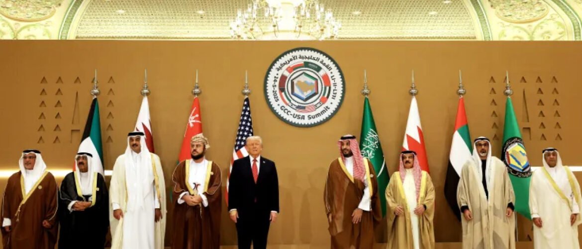 Group of world leaders in traditional robes and suits posing for a photo at an international summit, with flags and a circular summit emblem behind them.