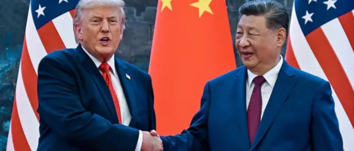 Two world leaders shake hands in front of red flags with yellow stars and US flags on either side, signaling a diplomatic meeting.